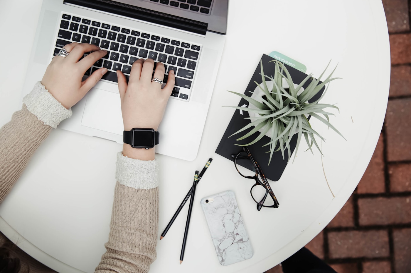 A calm desk with a laptop, notebook, pencils, glasses, and a plant